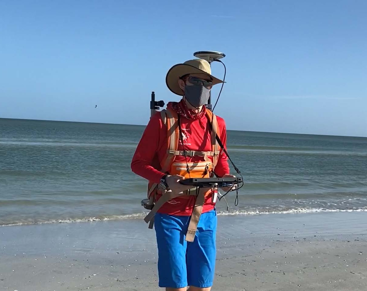 A USGS scientist uses a backpack GPS receiver and handheld computer to collect beach elevation data at Madeira Beach, Florida.